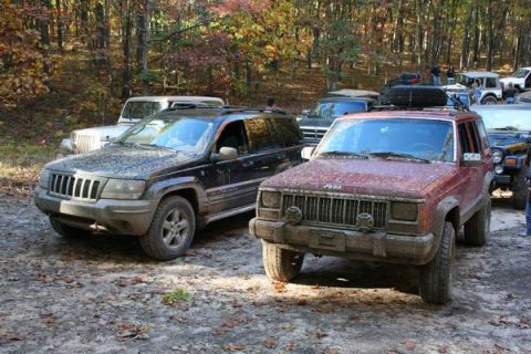 1992 Jeep Cherokee - Multiple Jeep SUVs are parked on a dirt path in a wooded area during autumn.