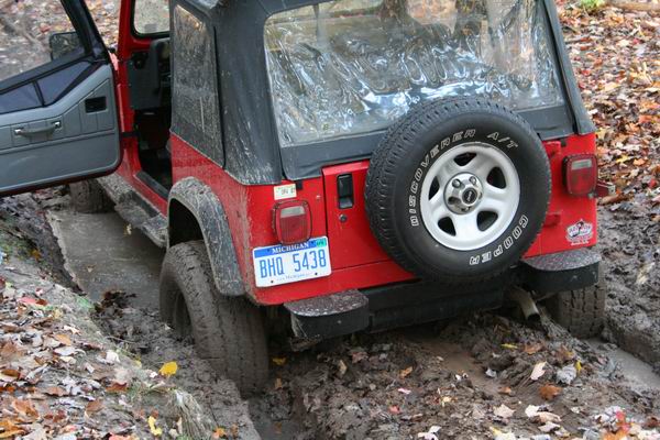 Red Jeep Wrangler stuck in mud, rear view, Michigan license plate BHQ 5438