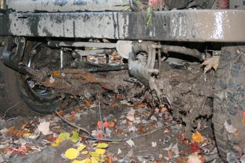 1992 Jeep Cherokee - A heavily mud-caked vehicle's undercarriage is visible, with suspension parts and a tire covered in mud and debris.
