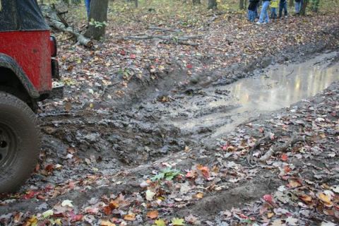 1992 Jeep Cherokee - A red Jeep Wrangler navigates a muddy off-road trail during autumn.