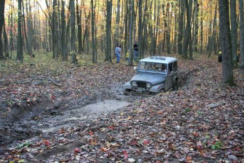 1992 Jeep Cherokee - Jeep CJ-7 navigating a muddy trail through a forest during autumn.