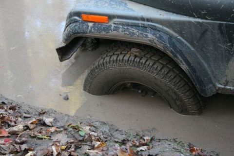 1992 Jeep Cherokee - This vehicle is stuck in a muddy puddle, with the tire submerged.