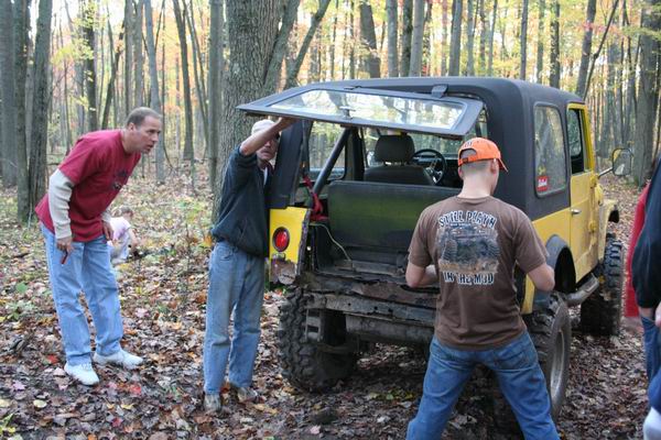 Yellow off-road vehicle with open rear hatch, mud tires, and visible rust on the rear bumper