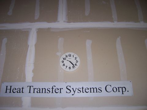 1991 Ford Bronco - A wall displays a clock and a company sign, with visible drywall seams and tape.