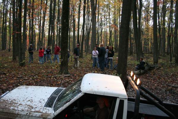 White pickup truck with roll bar and exhaust stacks in a forest