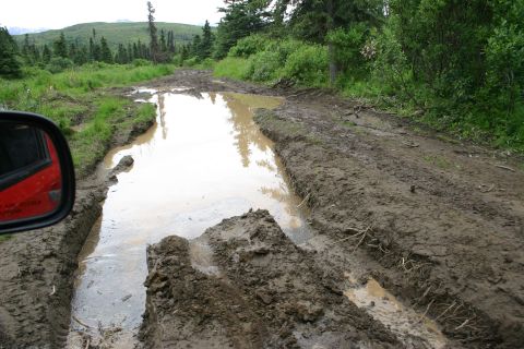 2003 Jeep TJ - Navigating a challenging muddy trail with deep puddles and rough terrain.
