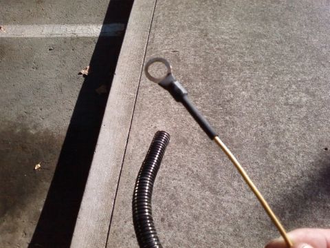 1995 Ford Bronco - A close-up shows a battery cable with a ring terminal and a section of black corrugated conduit on a concrete surface.