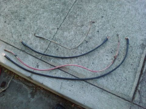 1995 Ford Bronco - Three automotive battery cables are laid out on a concrete surface.