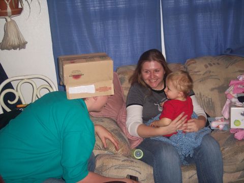1972 Ford Ranchero - A woman holds a baby while another person wears a cardboard box on their head on a couch.