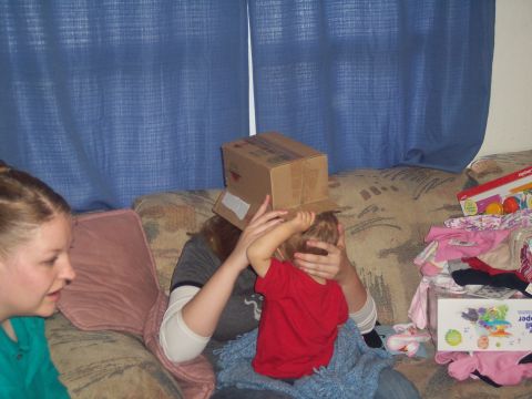 1972 Ford Ranchero - A child plays with a box on their head while sitting on a couch with other people and toys.