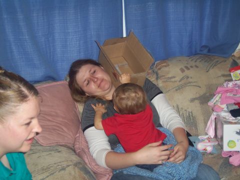1972 Ford Ranchero - A woman is holding a baby while a cardboard box rests on her head, with another person visible on the left.