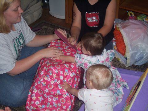 1972 Ford Ranchero - A woman and two babies are gathered around a large pink gift, possibly for a birthday or holiday celebration.