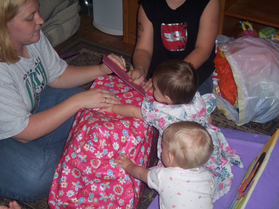 Woman and two babies gathered around a large pink gift