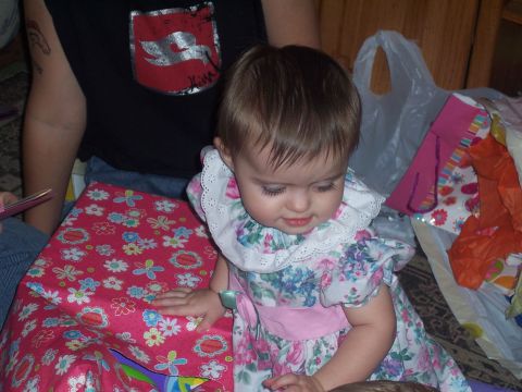 1972 Ford Ranchero - A baby wearing a floral dress and a white collar looks down near a gift-wrapped box.