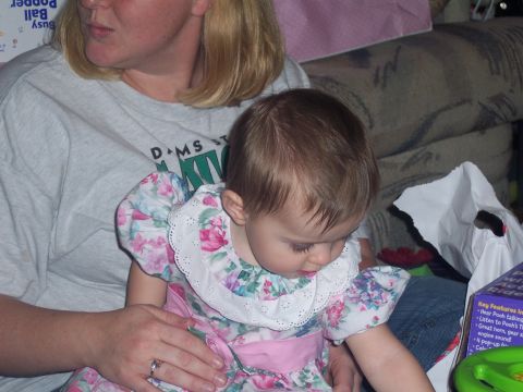 1972 Ford Ranchero - A woman holds a baby dressed in a floral outfit while sitting on a couch with gift bags nearby.