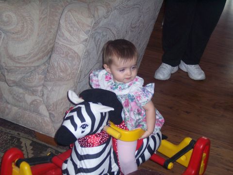 1972 Ford Ranchero - Baby enjoys a zebra rocking toy indoors, with an adult standing nearby.