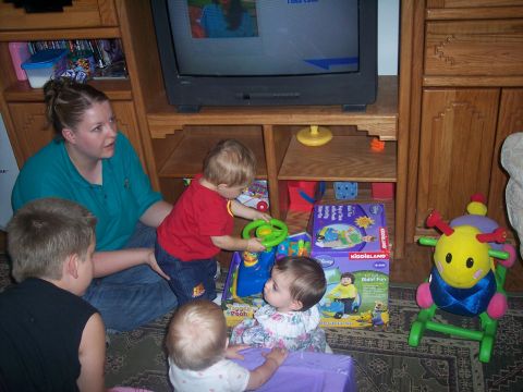 1972 Ford Ranchero - A group of children and a woman are gathered in a living room, watching television and playing near a television.