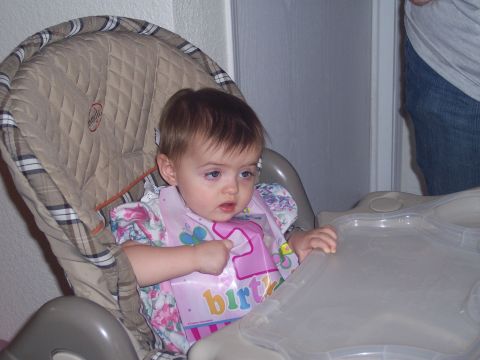 1972 Ford Ranchero - A baby sits in a high chair, wearing a pink bib with '1st birthday' printed on it, ready for a meal.