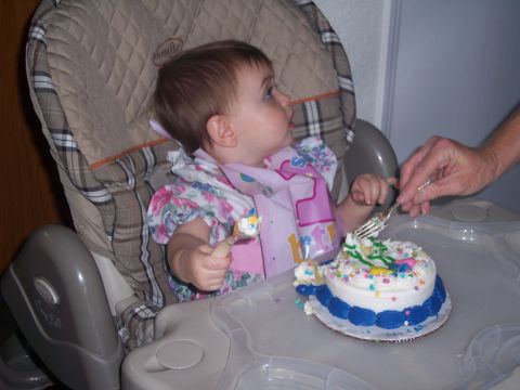 1972 Ford Ranchero - A baby sits in a high chair, wearing a bib and a floral dress, as they are about to eat a small, decorated cake.