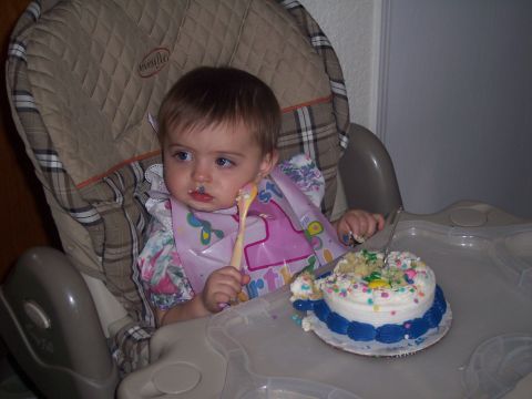 1972 Ford Ranchero - A baby sits in a high chair, holding a spoon and looking away from a messy cake.