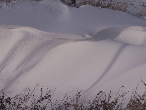 1972 Ford Ranchero - Snowfall has created undulating drifts, partially obscuring dry grass and casting a long shadow.