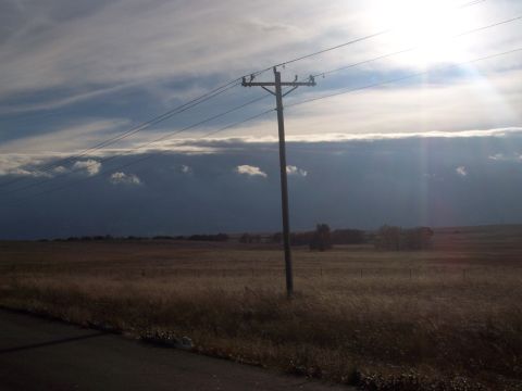 1972 Ford Ranchero - A solitary telephone pole stands in a vast, dry field under a dramatic sky with sunbeams breaking through dark clouds.