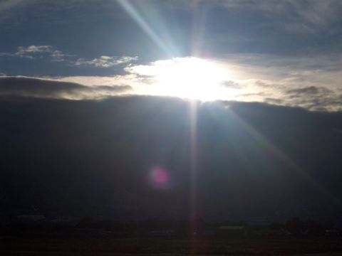 1972 Ford Ranchero - The sun's rays pierce through a thick layer of clouds, illuminating the sky above a dark horizon.