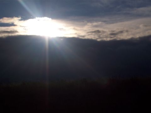 1972 Ford Ranchero - Sunlight breaks through dark clouds, illuminating the sky above a shadowed horizon.