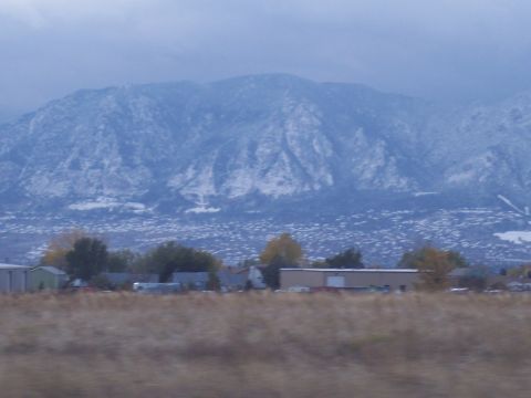 1972 Ford Ranchero - A vast mountain range dusted with snow overlooks a town and a field of dry grass under an overcast sky.
