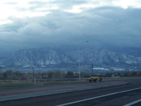 1972 Ford Ranchero - A yellow jeep drives along a road under a cloudy sky with distant snow-covered mountains.