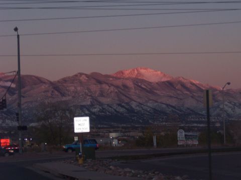 1972 Ford Ranchero - Snow-capped mountains are illuminated by the setting sun, with a road and traffic signs visible below.
