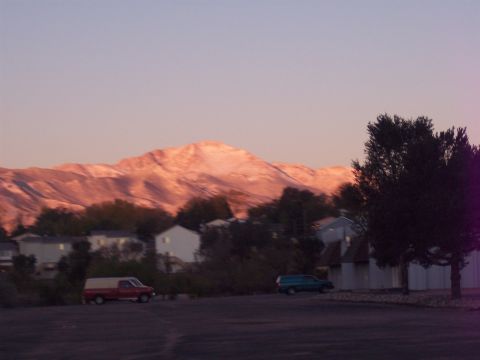 1972 Ford Ranchero - Two vehicles are parked in a lot with a mountain range illuminated by the setting sun in the background.