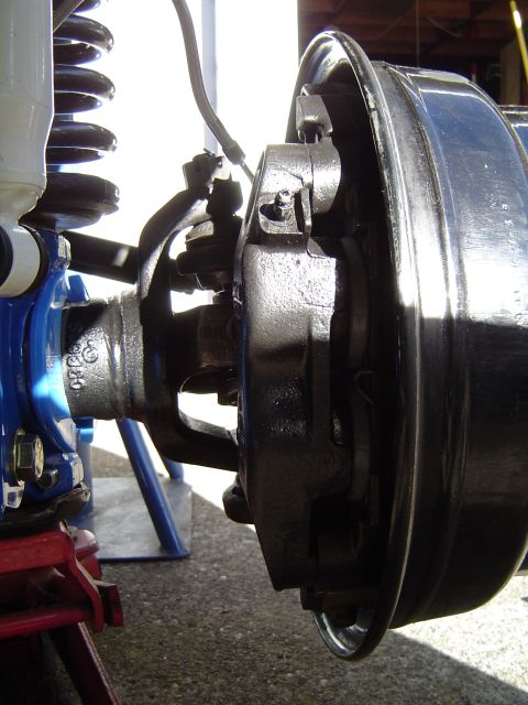 1978 Ford Bronco - Close-up view of a vehicle's front suspension and brake components, including a coil spring and brake drum.