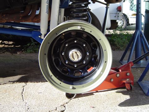 1978 Ford Bronco - Wheel and suspension components of a vehicle, possibly a 1978 Ford Bronco, are shown with a jack.