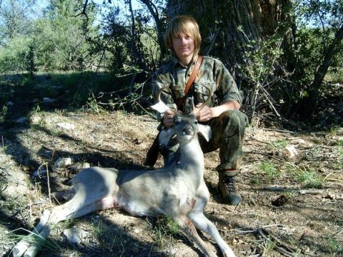 1983 Jeep CJ7 - A hunter poses with a deer he has harvested in a wooded outdoor setting.
