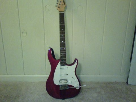 1995 Ford Bronco - A red electric guitar with a white pickguard stands on a carpeted floor.