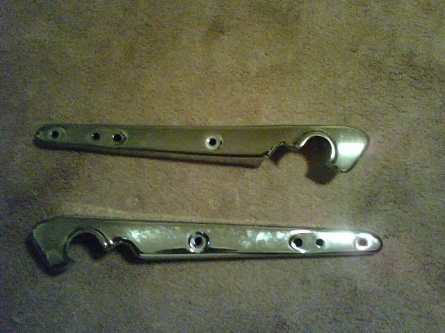 two chrome motorcycle exhaust pipes laid out on a brown carpet