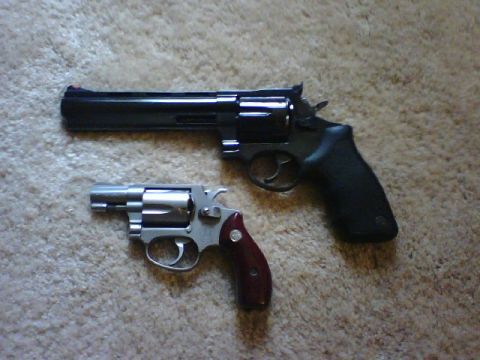 1995 Ford Bronco - A large black revolver and a smaller silver revolver with a dark red grip are placed on a carpeted surface.