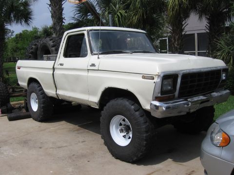 1979 Ford F-150 - A white 1979 Ford F-150 pickup truck with oversized tires is parked on a concrete surface.