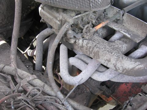 1979 Ford F-150 - The engine bay is filled with exhaust pipes and covered in grime.