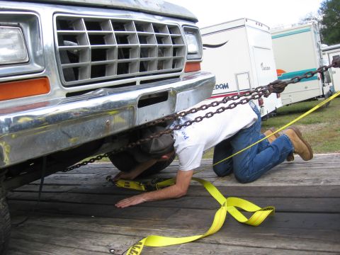 1979 Ford F-150 - A person secures a 1979 Ford F-150 to a trailer, with RVs visible in the background.