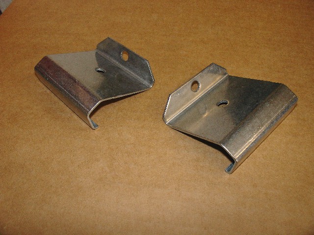 Two metal brackets with holes on a brown surface