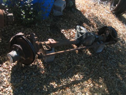 1973 Ford F-100 - A rusty Dana 60 axle assembly with brake components is shown outdoors on a bed of leaves.