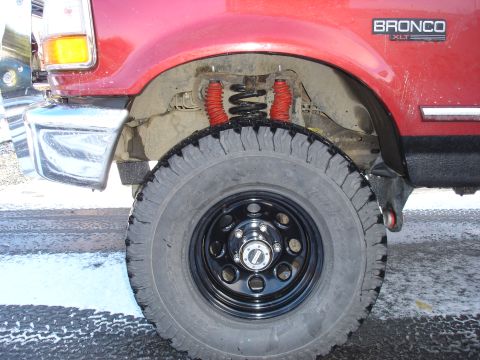 1996 Ford Bronco - A red Ford Bronco XLT is shown from the front quarter angle, focusing on the front wheel and fender area.