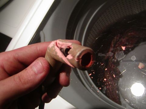 1991 Ford Bronco - Damaged spark plug wire boot with pink residue, held in front of a washing machine drum.