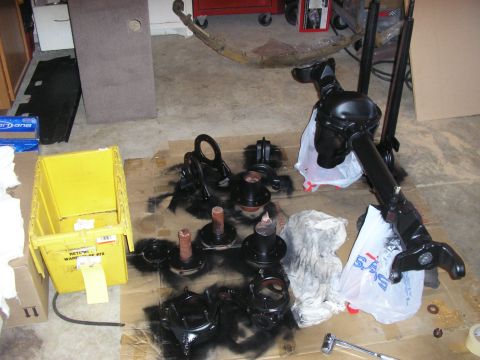 1996 Ford Bronco - Automotive parts, possibly for a Ford Bronco, are laid out on the floor for inspection or painting.