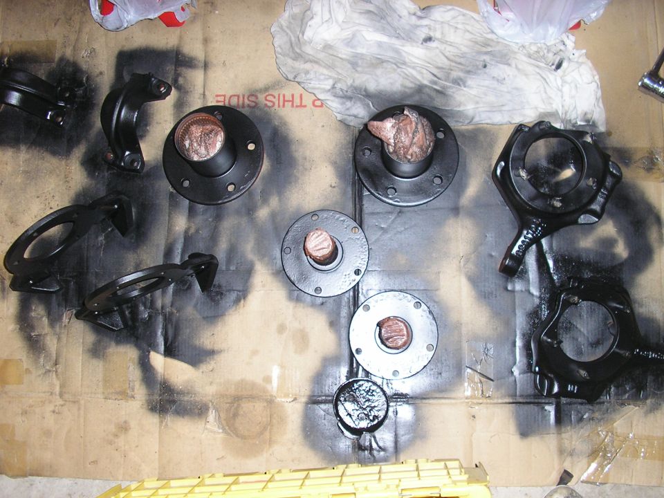 several black automotive parts laid out on cardboard, some with copper-colored centers