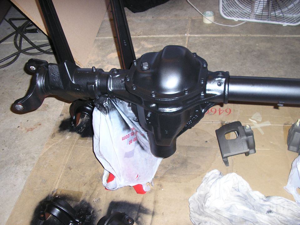 Black differential axle assembly with a white plastic bag underneath. Some parts are scattered around