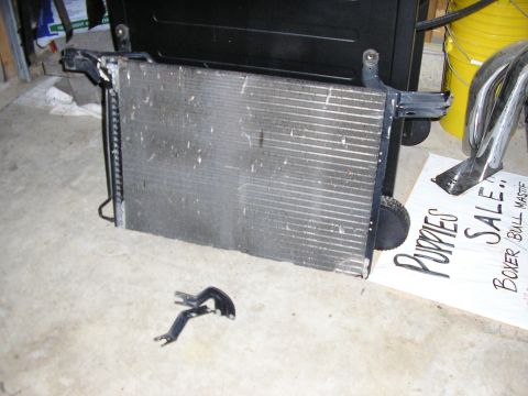 1996 Ford Bronco - A radiator is shown with its mounting hardware, next to a sign advertising puppies for sale.