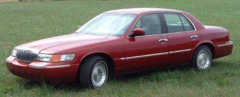 1999 Mercury Grand Marquis - A red 1999 Mercury Grand Marquis sedan sits on a grassy field.